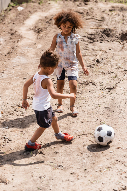 スラム街の汚い道でサッカーをしているアフリカ系アメリカ人の子供たちを憎む  - 写真・画像