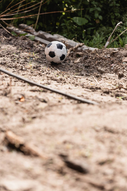 Selective focus of soccer ball on ground of dirty road on urban street  - Fotografie, Obrázek