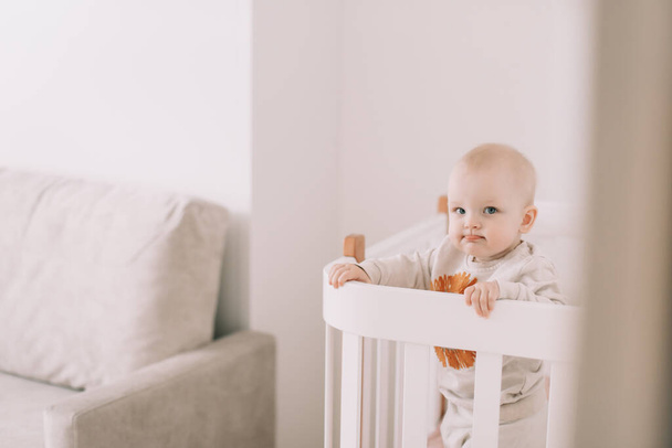 Cute little baby standing in crib at home. - Φωτογραφία, εικόνα