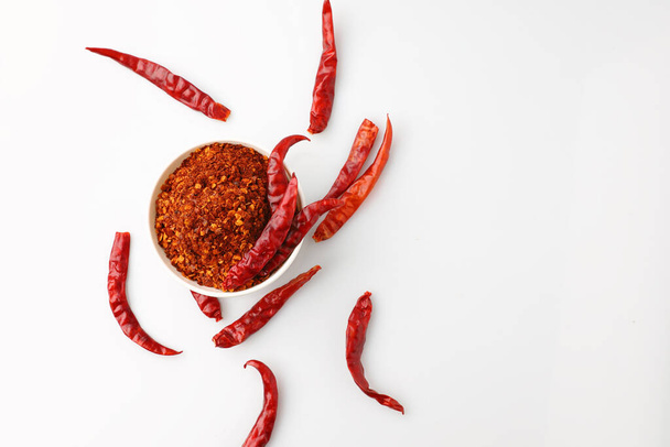 Top view επίπεδη lay πιπέρι καγιέν σε ένα λευκό κύπελλο με πολλά κόκκινα αποξηραμένα chilies. Απομονωμένο σε λευκό φόντο με αντιγραφικό χώρο. - Φωτογραφία, εικόνα