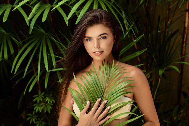 young smiling brunette woman with big green leaf on nature background , spa care people concept - Fotografie, Obrázek