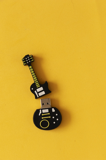 Disco estable usb en forma de guitarra sobre mesa amarilla. Archivos guardados en disco usb. - Zdjęcie, obraz