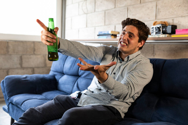handsome and elegant man watching tv and drinking beer at home in the living room - Foto, afbeelding