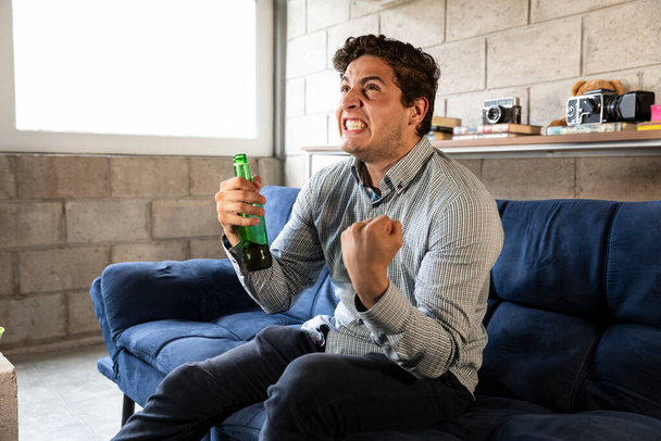 handsome and elegant man watching tv and drinking beer at home in the living room - Photo, Image