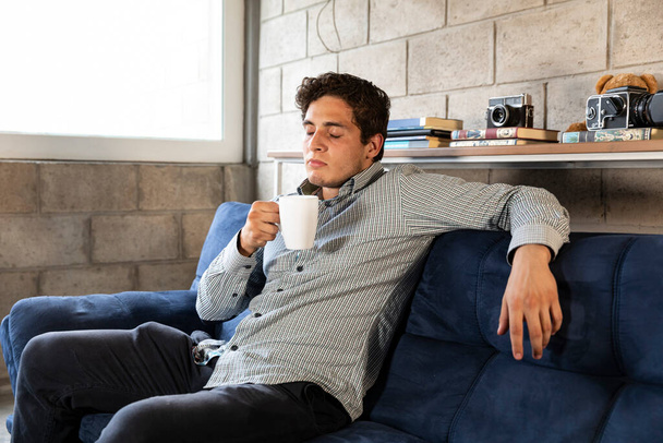 pohledný a elegantní muž pije kávu. během pandemie COVID-19 v obývacím pokoji - Fotografie, Obrázek