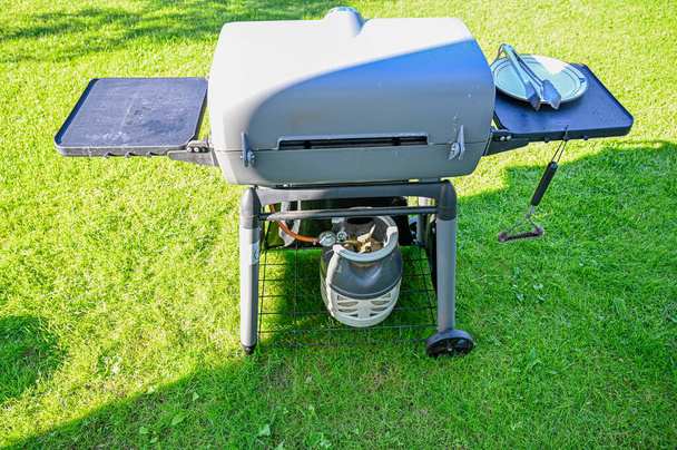 газовое барбекю в саду на зеленой траве
 - Фото, изображение