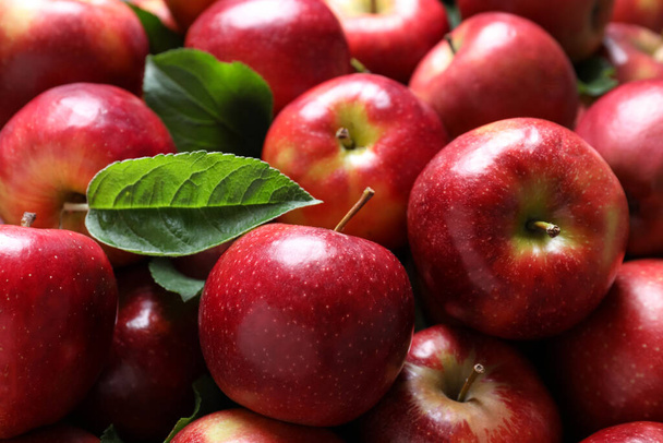 Pile of tasty red apples with leaves as background, closeup - Photo, Image