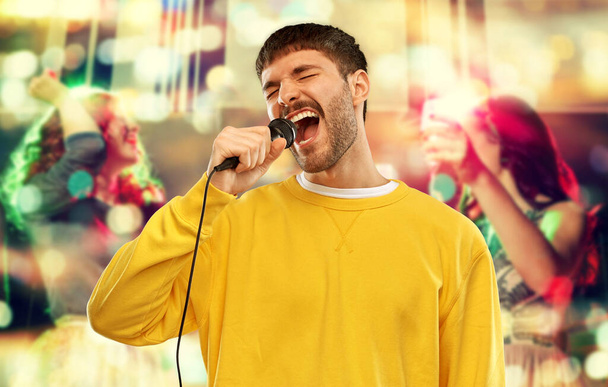 man with microphone singing at night club - Zdjęcie, obraz