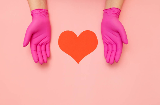 Close-up of hands in pink protective hold red heart. Cardiology concept. - Foto, Bild