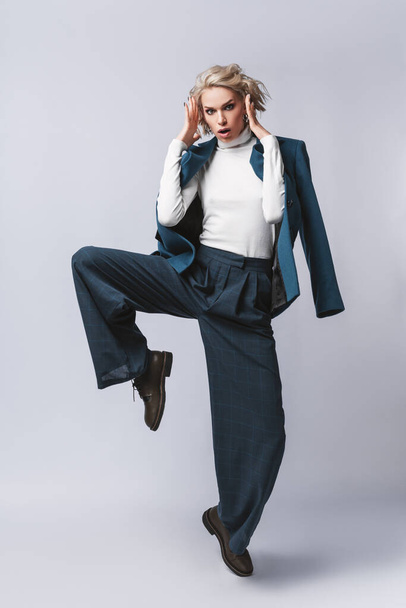 Fashion photo of a beautiful woman with blond nice hairstyle wearing  blue suit.Female beauty concept.Portrait of fashionable young girl dressed just in classic jacket.Studio shot.Hight fashion look.elegant woman. - Fotó, kép