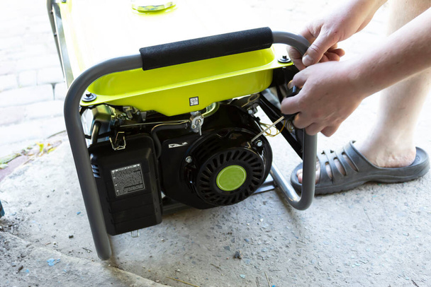 A man pulls the starter cord to start the generator - an additional source of energy. - Φωτογραφία, εικόνα