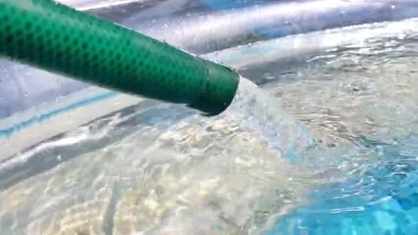 El agua fluye desde la manguera hacia la piscina inflable de llenado. Día soleado de verano, al aire libre
 - Metraje, vídeo