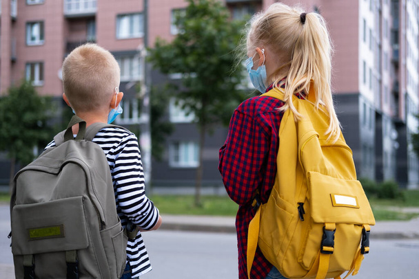 back view Brother and sister going school after pandemic over. Kids wearing mask and backpacks protect and safety from coronavirus for back to school. students are ready for new school year - Foto, Bild