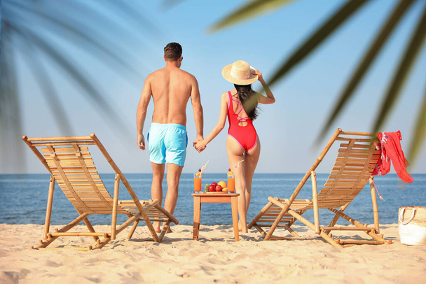 Couple resting on sunny beach at resort - Photo, image