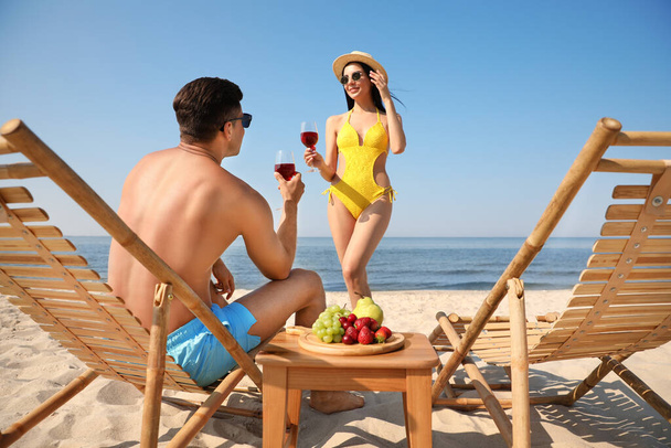 Happy couple with wine on sunny beach at resort - Фото, изображение