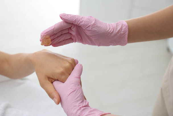 Woman getting wax epilation of hand in salon, closeup - Fotó, kép