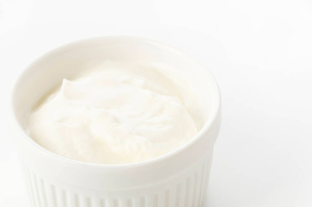 Свіжий грецький йогурт у керамічному білому рамеккіні на білому тлі - Фото, зображення