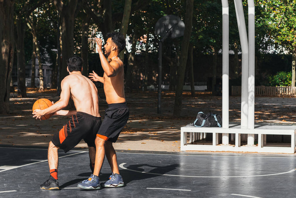 deux jeunes hommes jouant au basket à l'extérieur - Photo, image