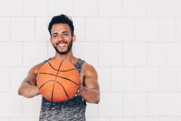 young man holds a basketball while smiling - Foto, Imagen