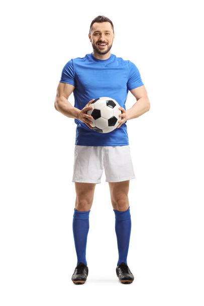 Full length portrait of a soccer player holding a ball and looking at the camera isolated on white background - Valokuva, kuva