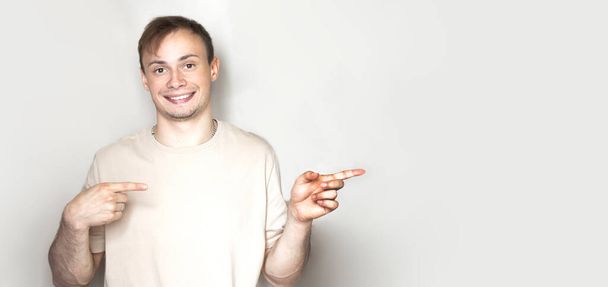 Portrait of an excited happy man pointing finger up at copyspace isolated on a white background - 写真・画像