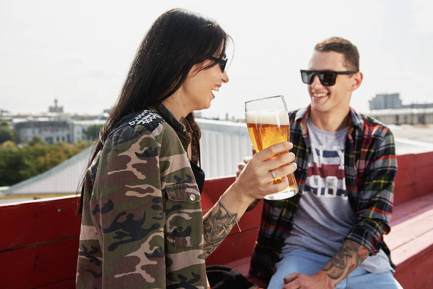 Happy smiling couple toasting and drinking beer at outdoor pub or bar on rooftop at summer, copy space - Fotografie, Obrázek