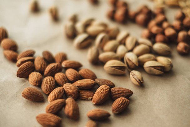 Different types of nuts, nut mix of almonds, hazelnuts, cashews, peanuts on a craft paper. High quality photo - Fotografie, Obrázek