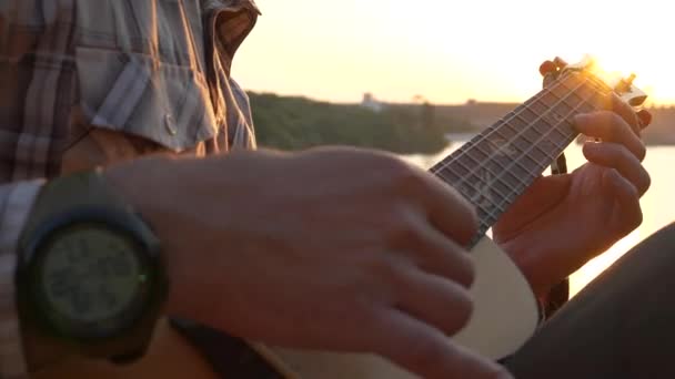 Ein Musiker spielt auf der Ukulele in Nahaufnahme seiner Hände und dem Griffbrett einer Gitarre. - Filmmaterial, Video