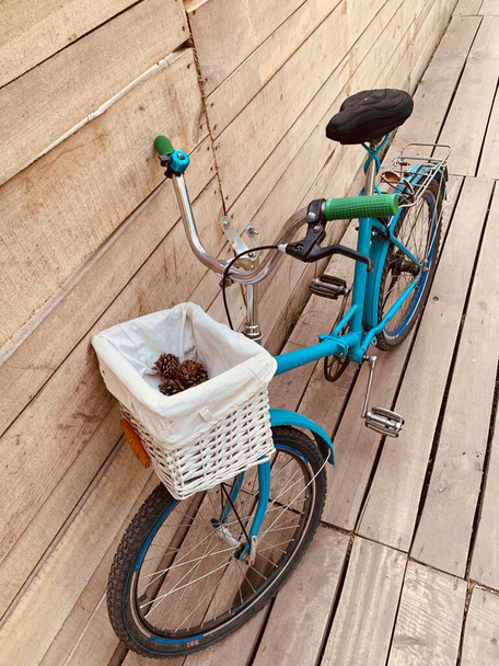 Top view of blue vintage bicycle with cute white basket at wooden background , weekend bike  ride, ecologic transport  - Photo, Image