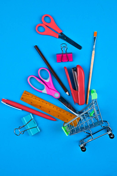Trolley with office supplies on a blue background. High quality photo - Photo, Image