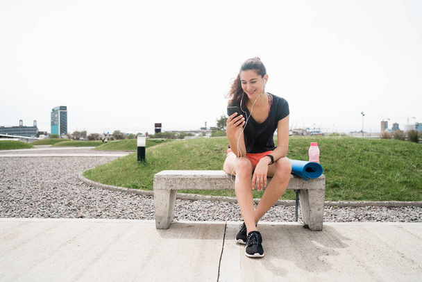 Portrait of an athletic woman using her mobile phone on a break from training. Sport and health lifestyle. - Photo, image