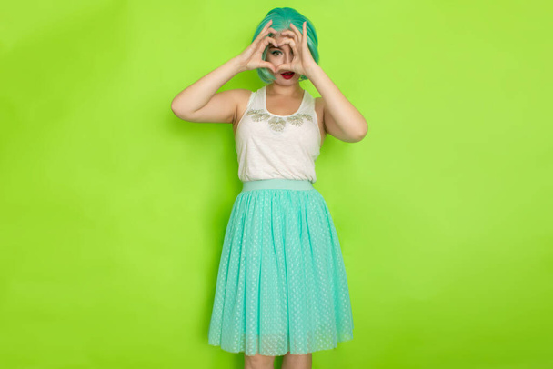 Portrait of a beautiful young woman with short blue hair in a studio on a green background. Mid-length romantic skirt and white blouse - Foto, immagini