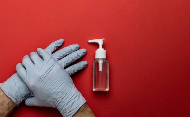 Medical background red. Medical antibacterial sanitizer gel and lab gloves on Virus protection equipment background. Clear sanitizer in pump bottle. Novel Coronavirus 2019-nCoV - Foto, Imagen