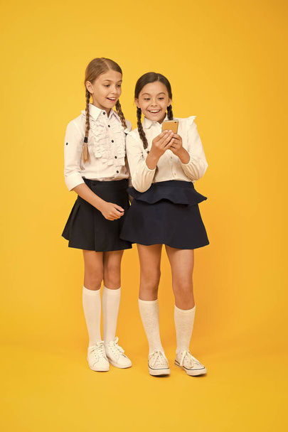 Internet is wonderful resource but access to it has hazards for kids. Girls school uniform using smartphone. Schoolgirls use mobile phone or smartphone to share photos. School application smartphone - Photo, Image