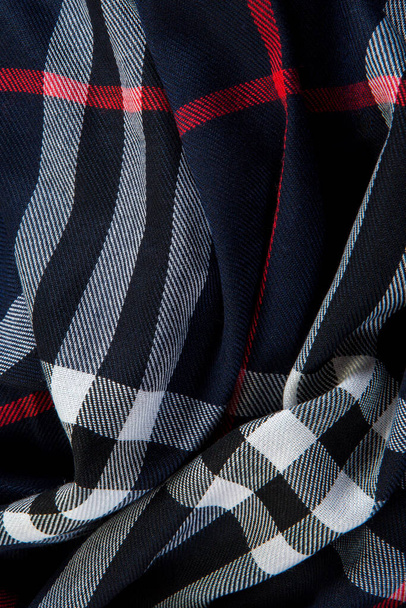 vertikale Ansicht von oben Nahaufnahme zerknittert schwarz karierter Schal mit weißen und roten Streifen - Foto, Bild