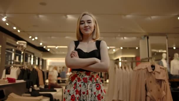 Bella donna in piedi con le braccia incrociate al coperto di negozio di vestiti alla moda - Filmati, video