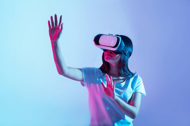 Εικονικό παιχνίδι νέας γενιάς. Κορίτσι με γυαλιά που εξετάζει κάτι και σηκώνει τα χέρια - Φωτογραφία, εικόνα