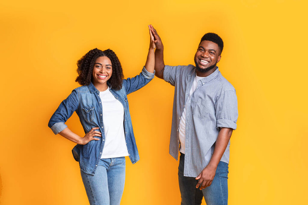 Teamwork In Relationship. Joyful Black Couple High-Fiving Each Other Over Yellow Background - Photo, Image
