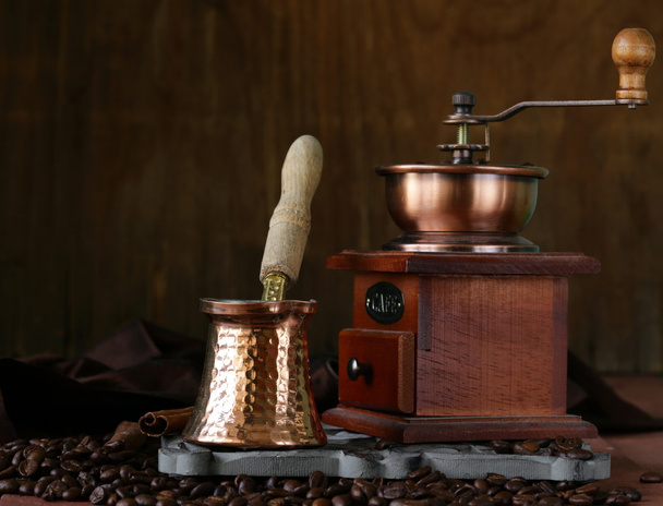 Copper coffee pot with beans on a wooden table - Fotó, kép
