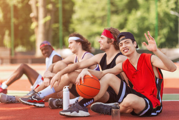 Group of basketball players resting at outdoor court after match, free space - Photo, Image