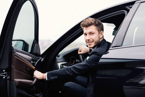 Jonge zakenman rijdt alleen in zijn luxe auto - Foto, afbeelding