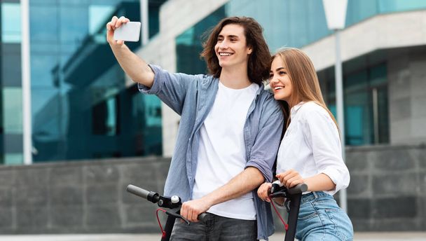 Freunde fahren auf motorisierten Tretrollern und machen Selfies - Foto, Bild