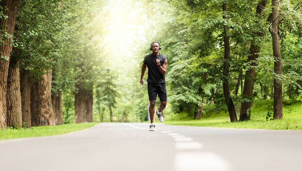 Motivated african sportsman jogging at city park - Photo, Image
