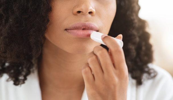 Remédios de lábios rachados. Closeup de mulher negra aplicando Chapstick hidratante Lip Balm
 - Foto, Imagem