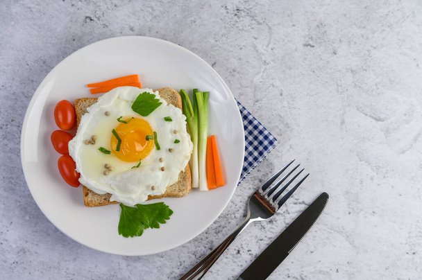 Un œuf frit posé sur un pain grillé, surmonté de graines de poivre avec des carottes et des oignons de printemps. - Photo, image