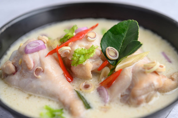 Tom Kha Kai in a pan frying with kaffir lime leaves, lemongrass, red onion, galangal and chilli.Selective focus. - Фото, изображение