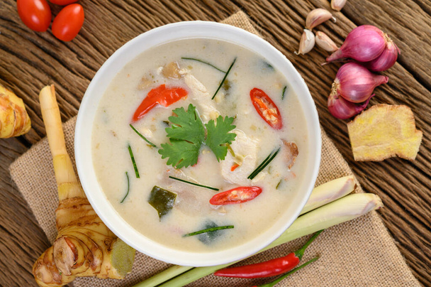 Tom Kha Kai in a bowl with kaffir lime leaves, lemongrass, red onion, galangal and chilli. - Фото, изображение