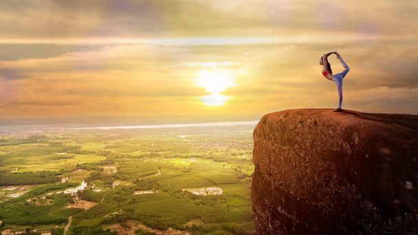 žena cvičí jógu na vrcholu hory se západem slunce nebo východem slunce - Fotografie, Obrázek