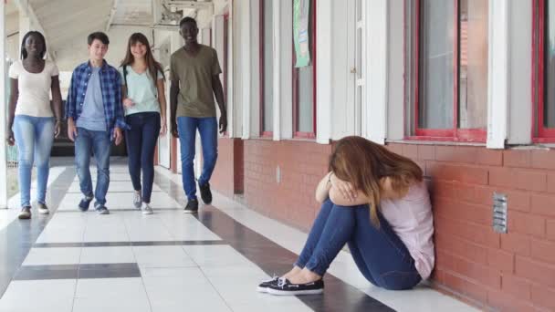 Asiatisches Mädchen, das in der Schule von vier Schülern gemobbt wurde, sitzt auf dem Schulflur. Zeitlupe - Filmmaterial, Video