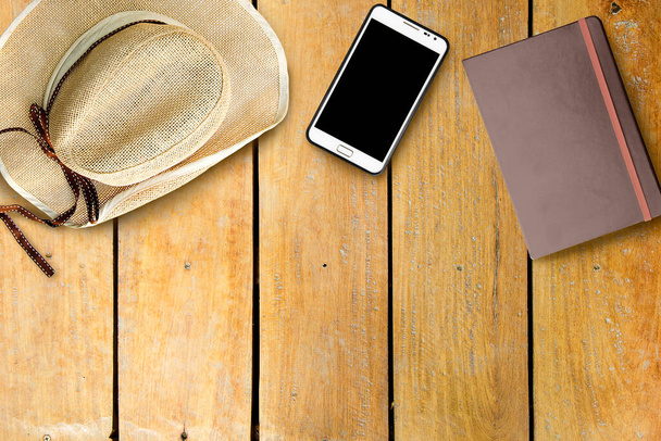 Overhead smartphone hat and notebook on old wooden desk - Photo, Image